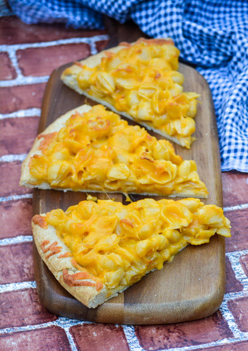 slices of baked mac and cheese pizza on a wooden cutting board