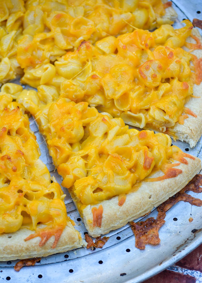 slices of baked mac and cheese pizza on a silver pizza pan