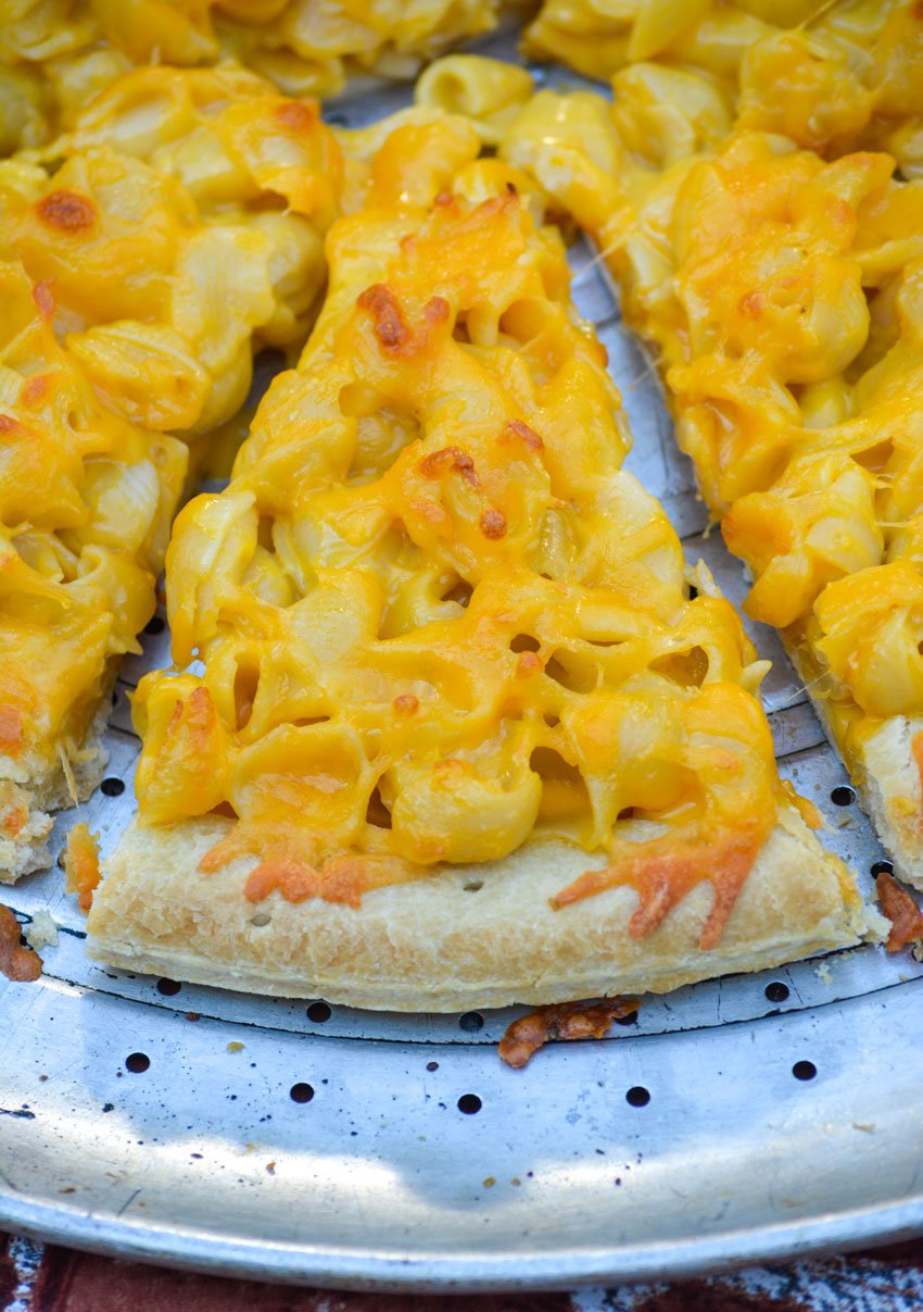 slices of baked mac and cheese pizza on a silver pizza pan