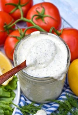 a wooden spoon scooping homemade tartar sauce out of a small glass jar