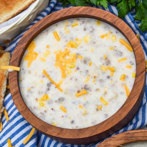 sausage and grits chowder in two wooden bowls with slices of toast on the side