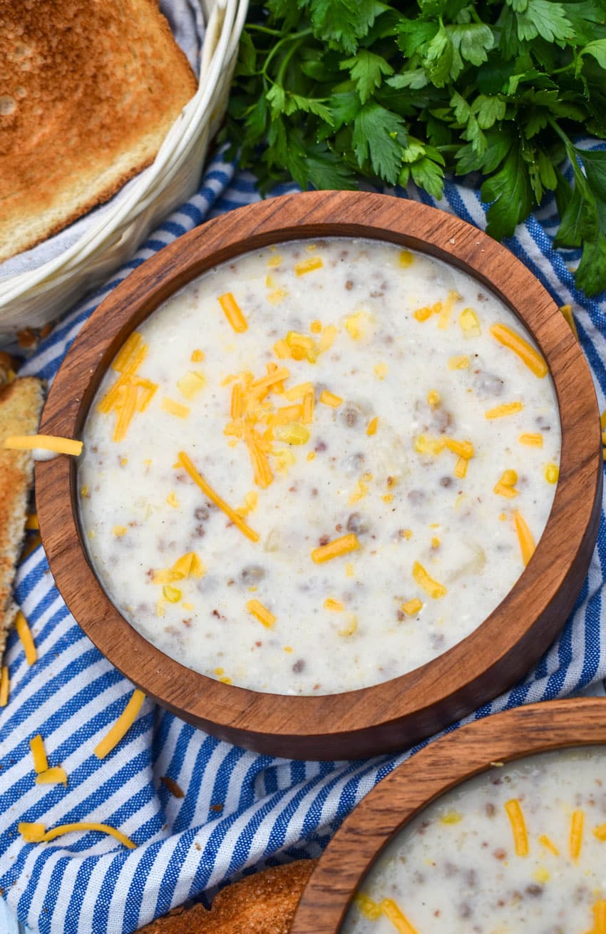 sausage and grits chowder in two wooden bowls with slices of toast on the side