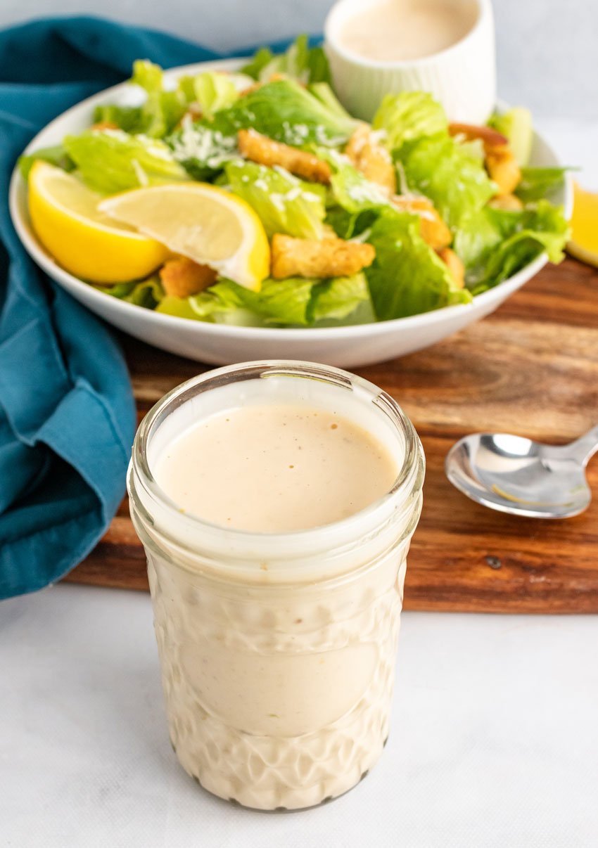a glass jar filled with homemade caesar salad dressing