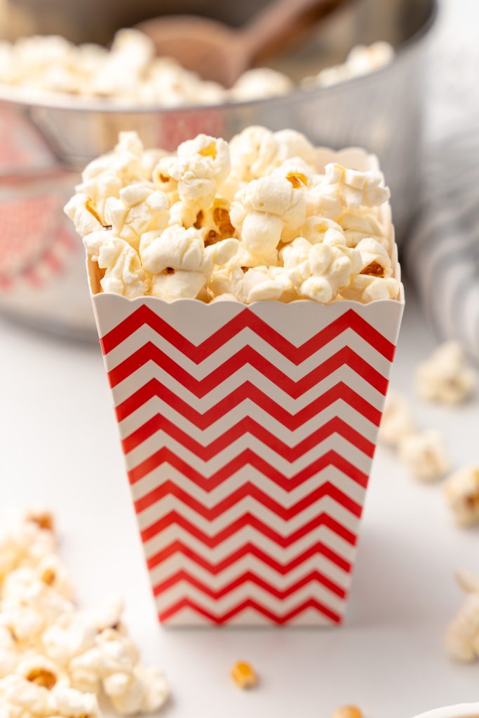 homemade kettle corn in a red and white striped paper popcorn holder