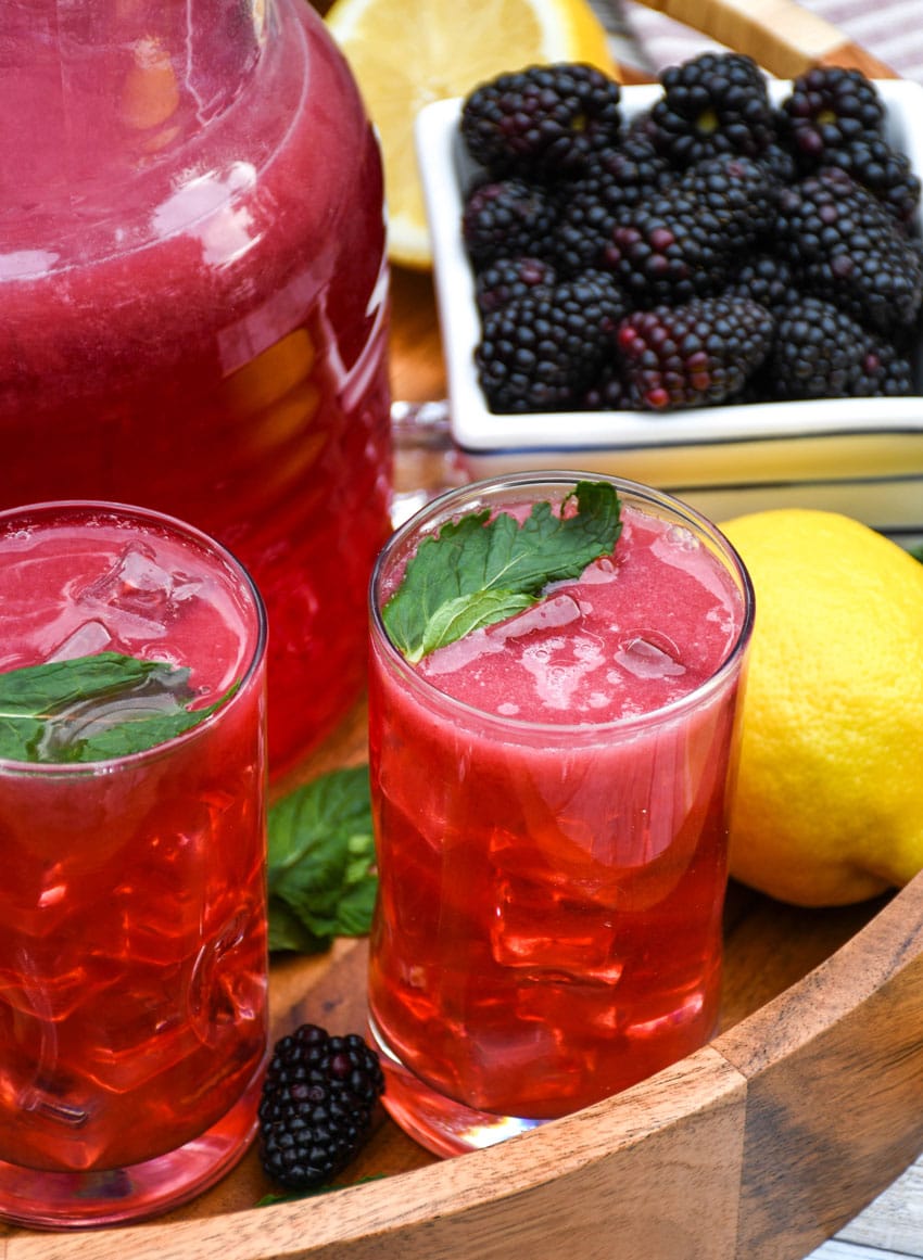 blackberry lemonade in two small glasses on a wooden serving tray