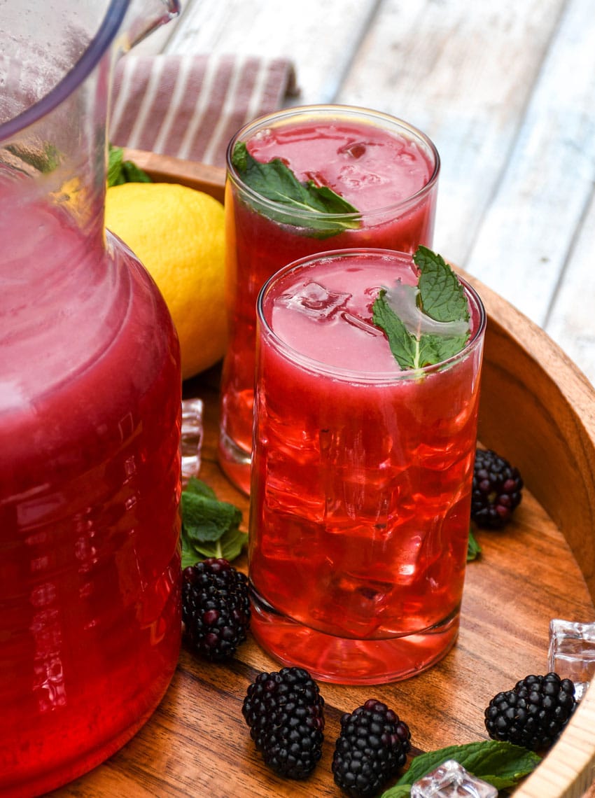 blackberry lemonade in two small glasses on a wooden serving tray