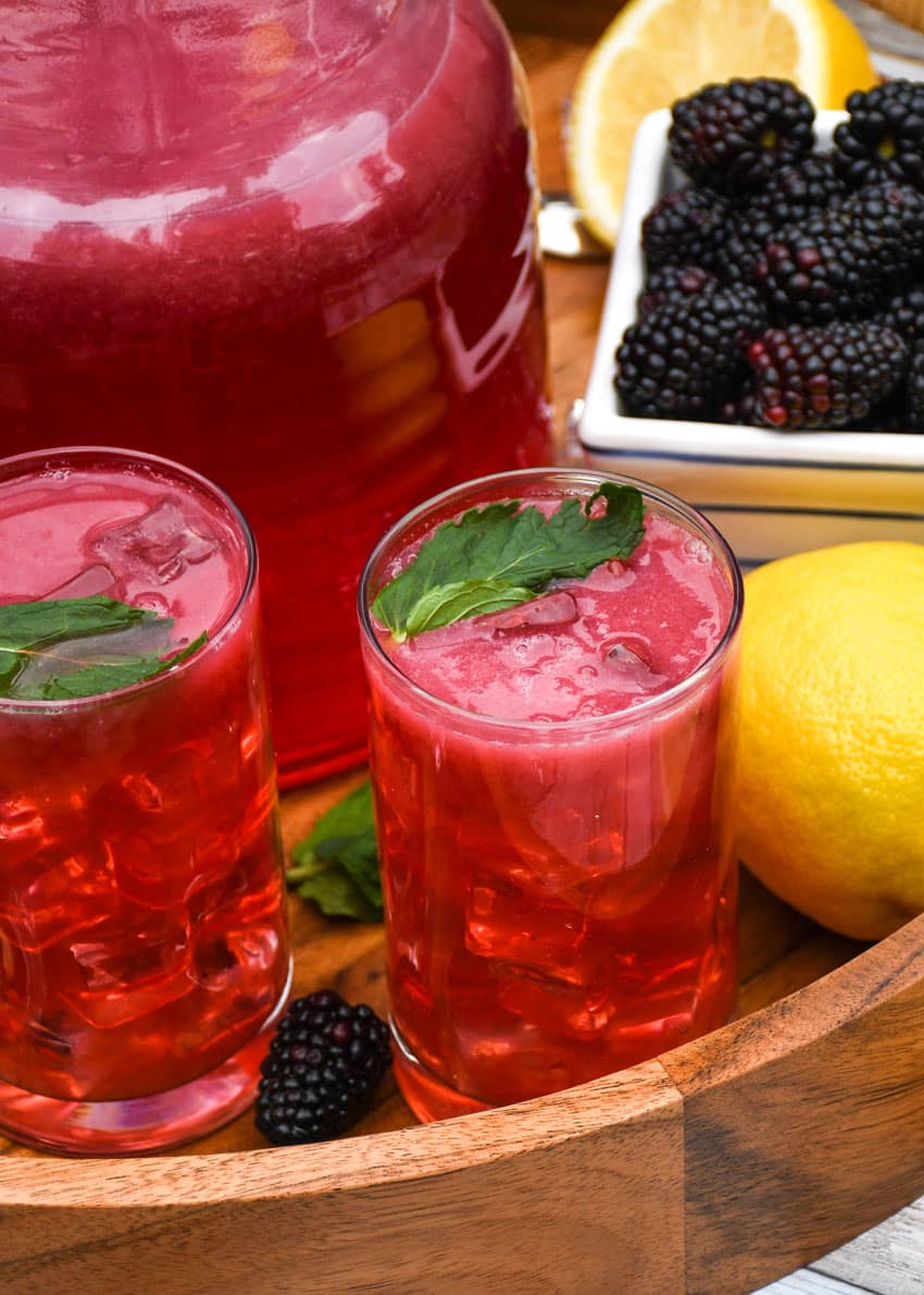 blackberry lemonade in two small glasses on a wooden serving tray