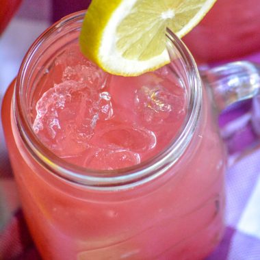 fresh blackberry lemonade in a glass topped with a fresh slice of lemon