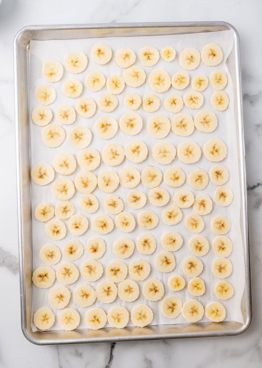 banana slices on a parchment paper lined baking sheet