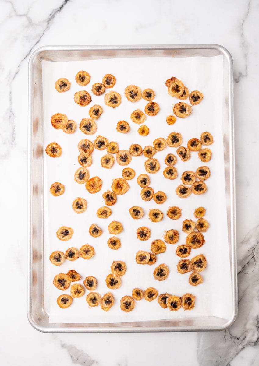 baked homemade banana chips on a parchment paper lined baking sheet