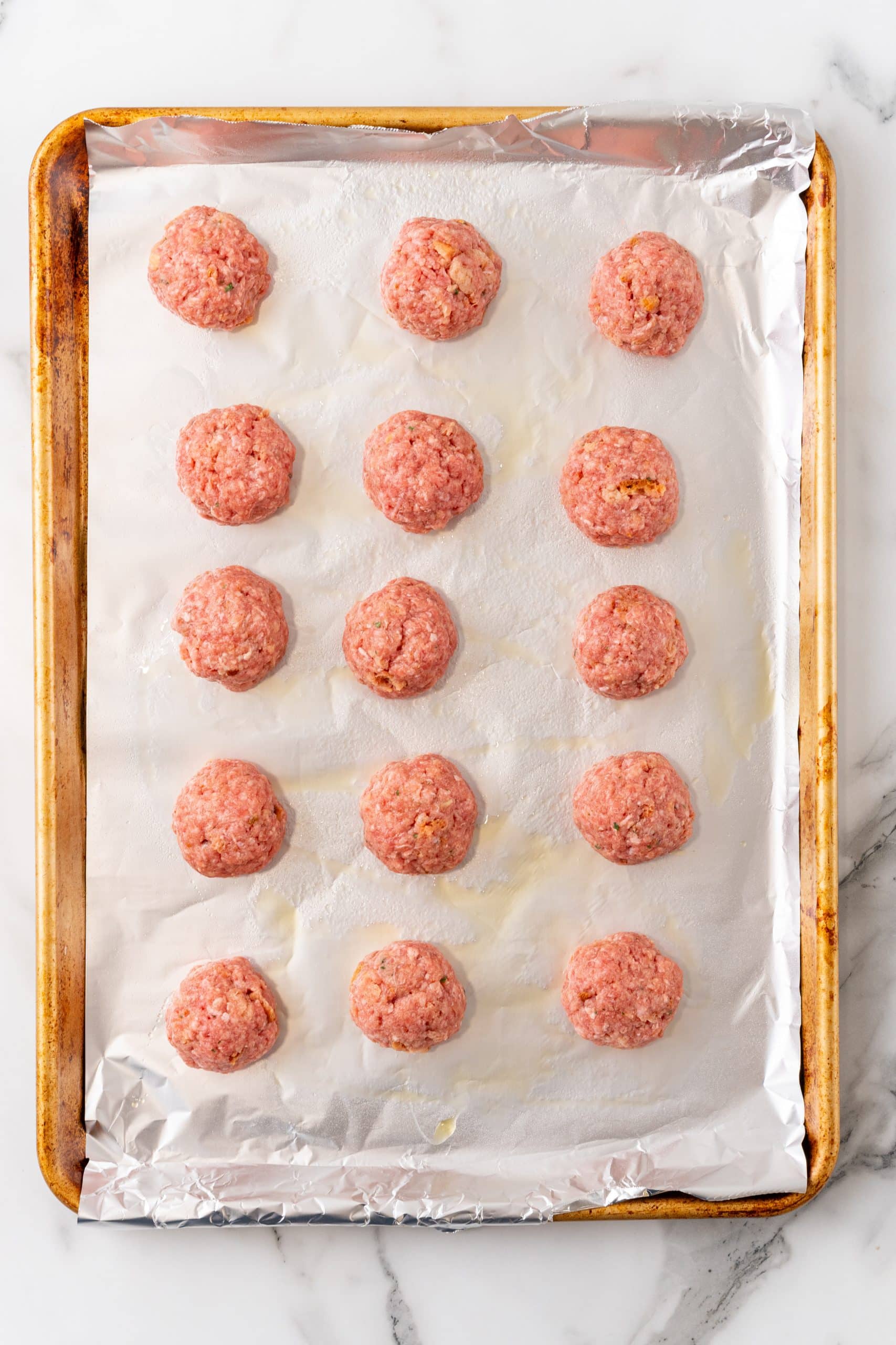 easy baked meatballs arranged on a foil lined baking sheet