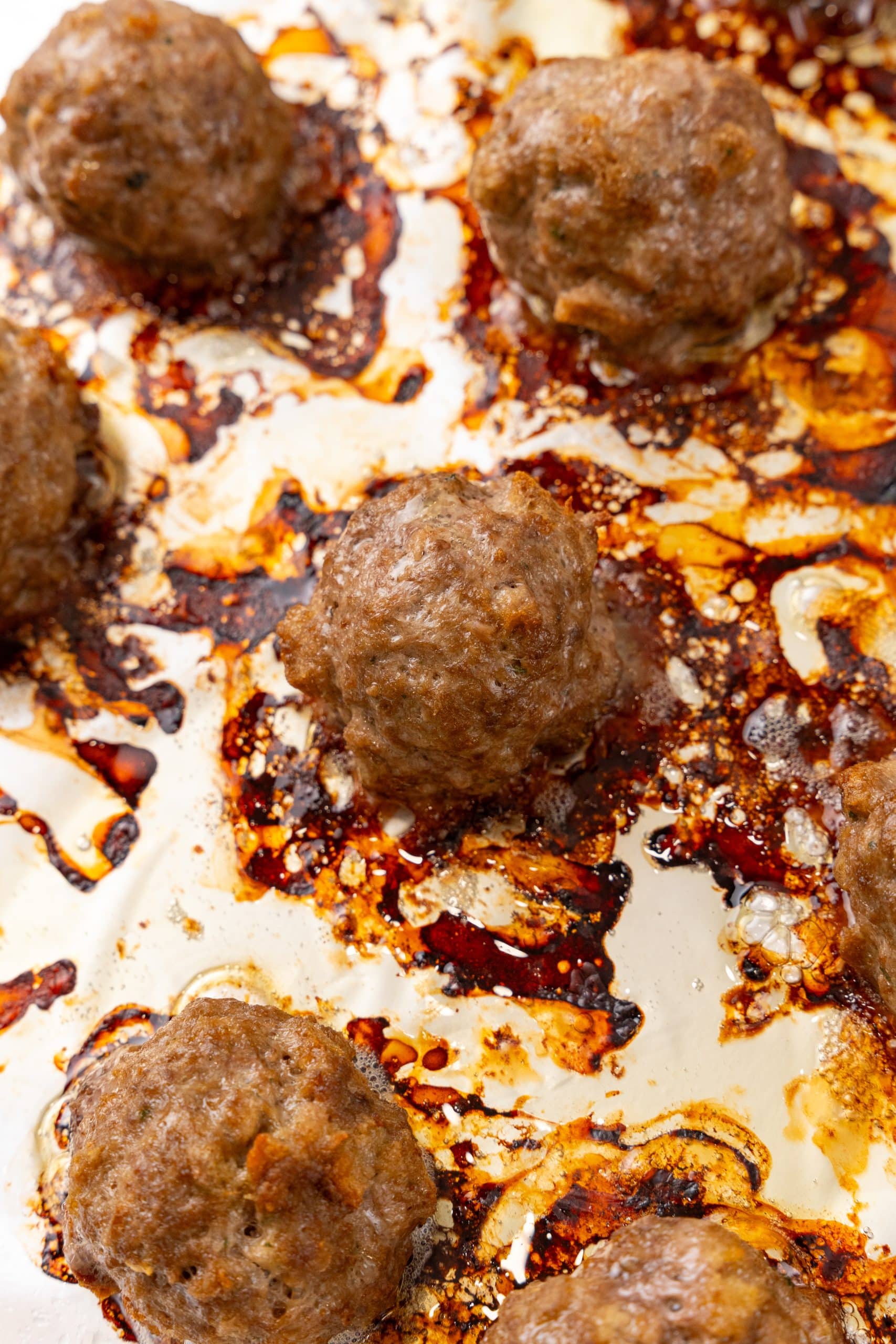 easy baked meatballs arranged in rows on a foil lined baking sheet