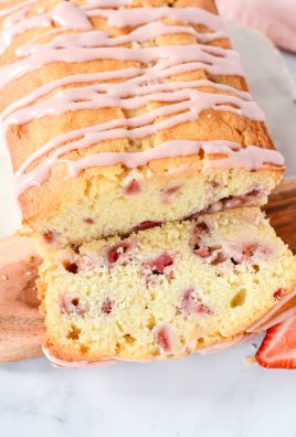 strawberry bread with cream cheese glaze served on a wooden cutting board on a marbled background