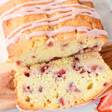 strawberry bread with cream cheese glaze served on a wooden cutting board on a marbled background