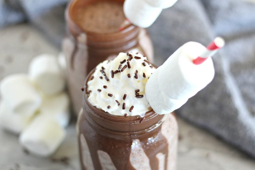 this frozen hot chocolate dessert recipe is served in chocolate syrup coated glass jars with marshmallow topped paper straws