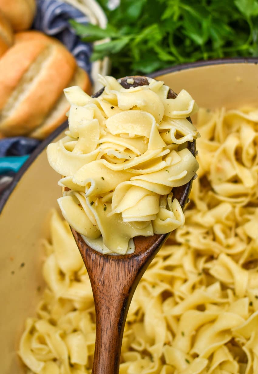 a wooden spoon holding up a scoop of easy garlic butter egg noodles
