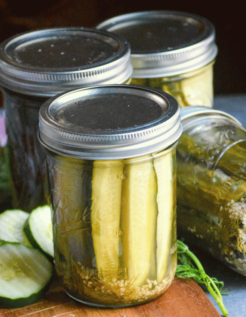 mason jars filled with refrigerator pickles shown on a wooden cutting board