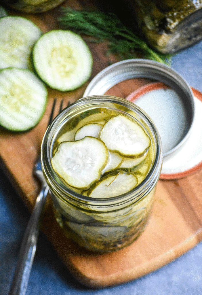 a glass jar filled to the brim with brine and sliced dill & garlic refrigerator pickles