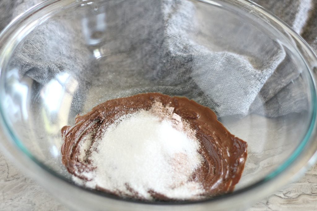 ingredients being added to a glass mixing bowl to make frozen hot chocolate