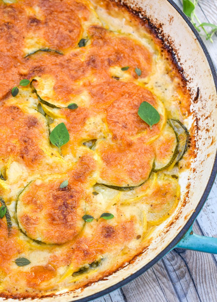 zucchini and squash au gratin in a blue enameled cast iron skillet