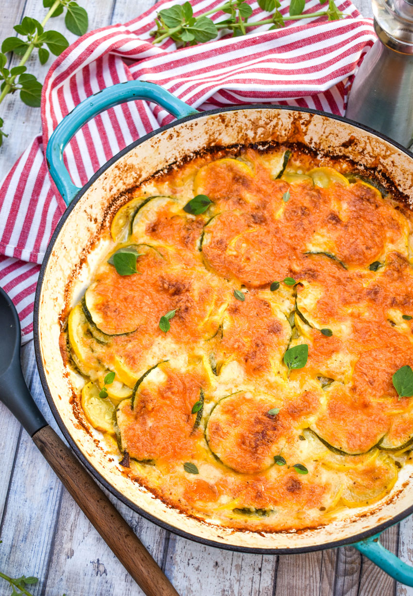 zucchini and squash au gratin in a blue enameled cast iron skillet