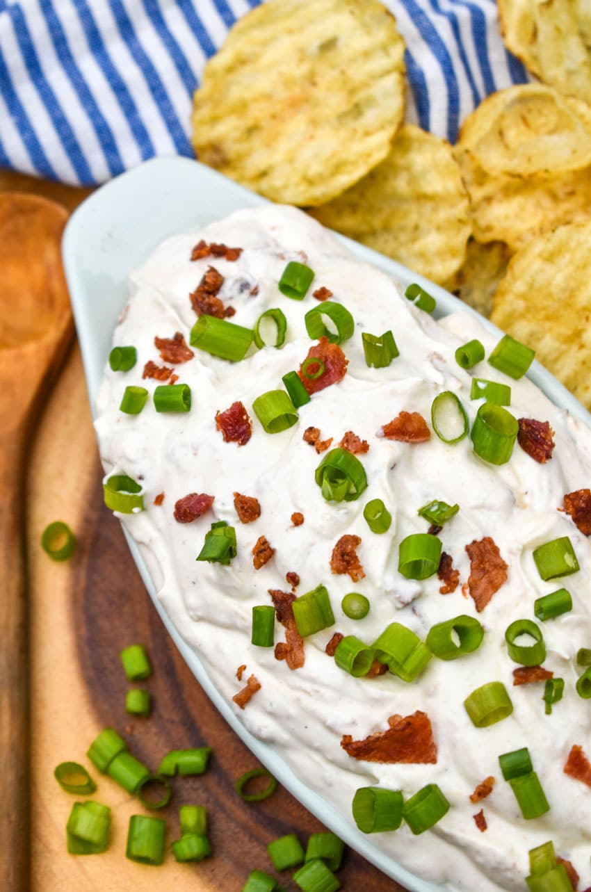 creamy bacon horseradish dip in a small serving dish surrounded by potato chips