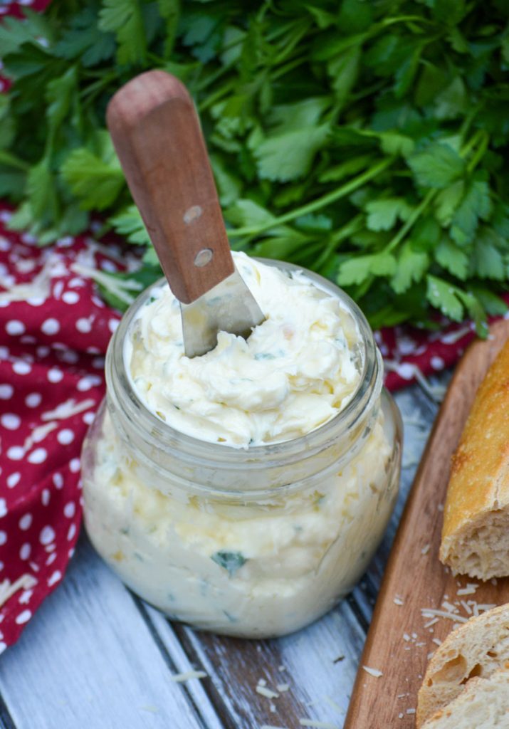 Italian garlic butter spread shown in a glass mason jar with a wooden handled spreader stuck in it