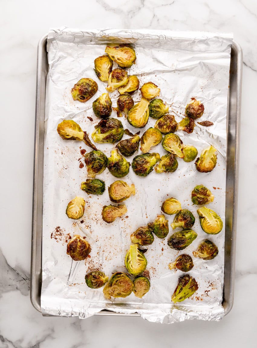 roasted brussels sprouts on an aluminum foil lined baking sheet pan