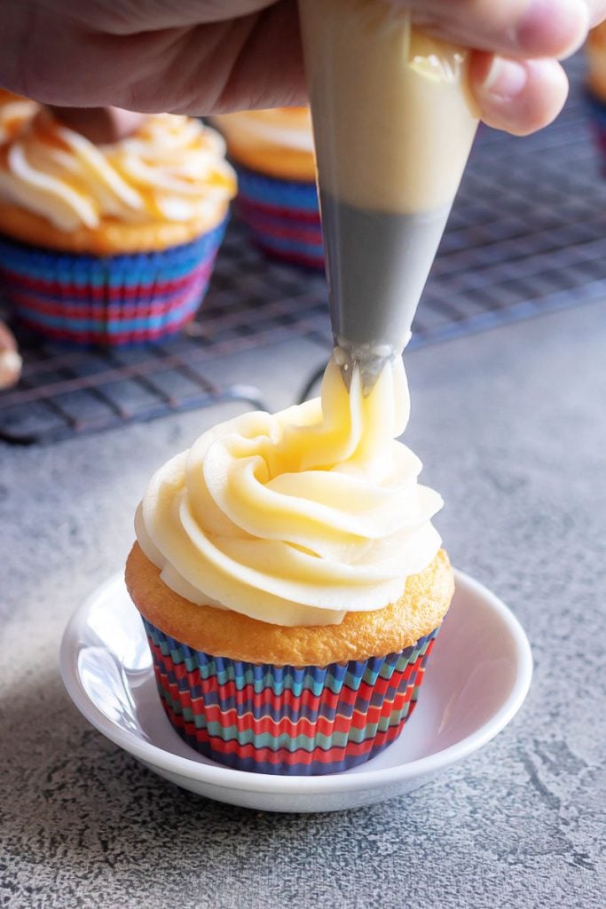 Baby Ruth Cupcakes shown with the buttercream frosting being piped on