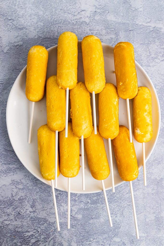 twinkies inserted with white popsicle sticks shown on a white plate