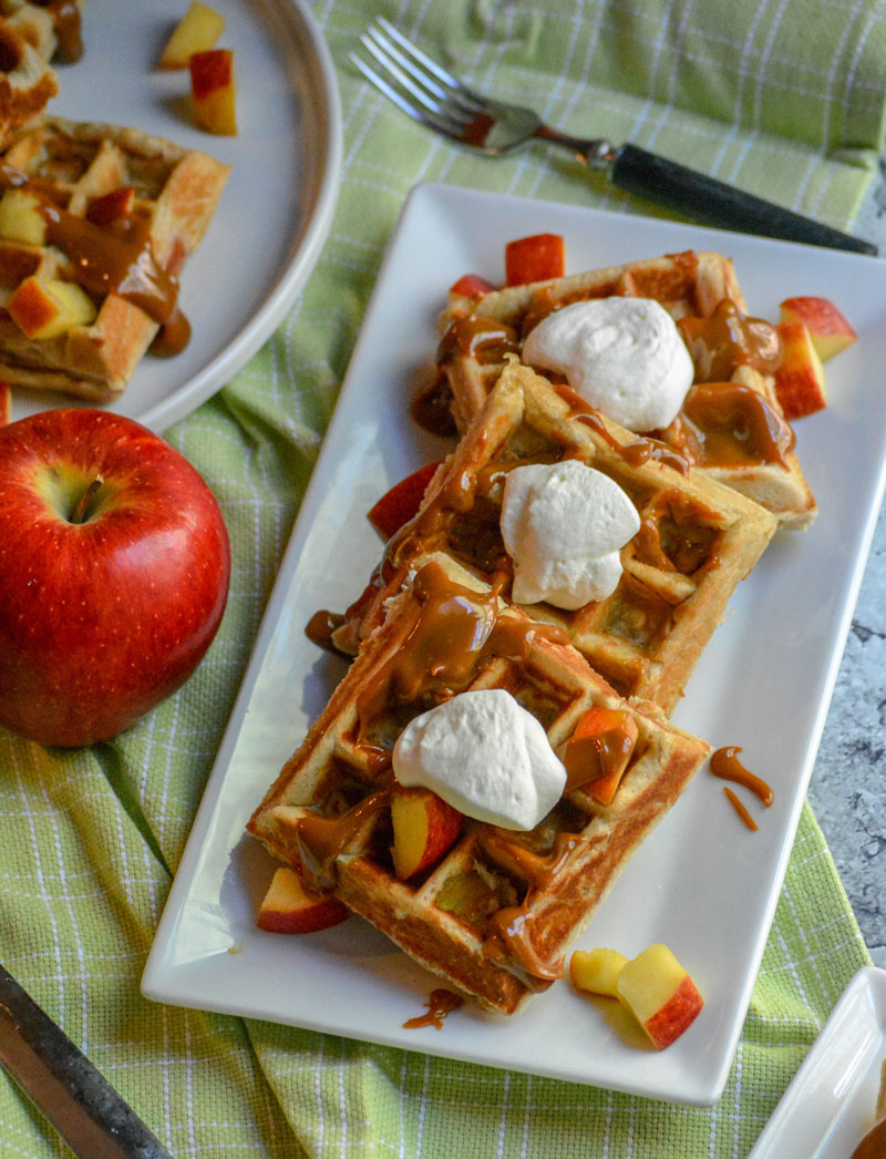 CARAMEL APPLE STUFFED BELGIAN WAFFLES TOPPED WITH WHIPPED CREAM AND DICED APPLES ON A WHITE SERVING PLATTER