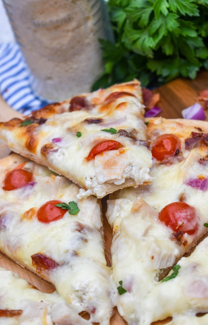 garlic chicken bacon ranch pizza on a wooden pizza peel