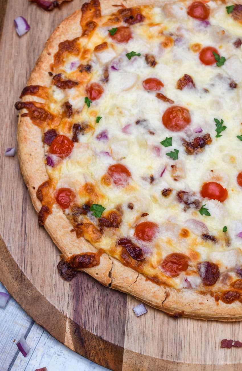 garlic chicken bacon ranch pizza on a wooden pizza peel