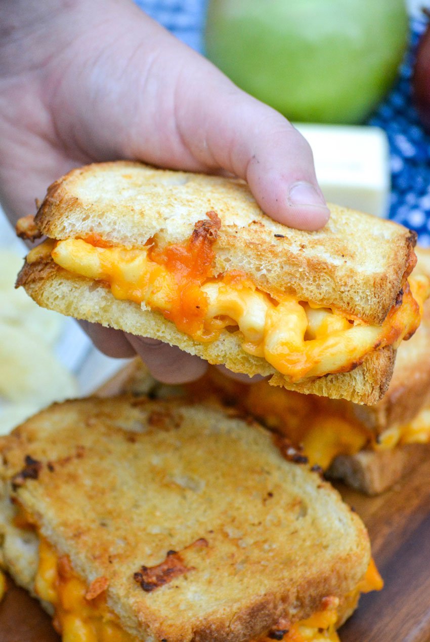 a hand holding up half a grilled mac and cheese sandwich