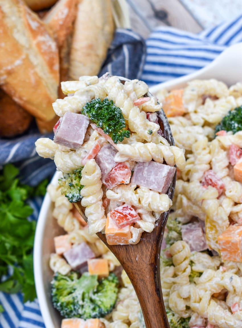 a wooden spoon holding up a scoop of creamy ranch pasta salad