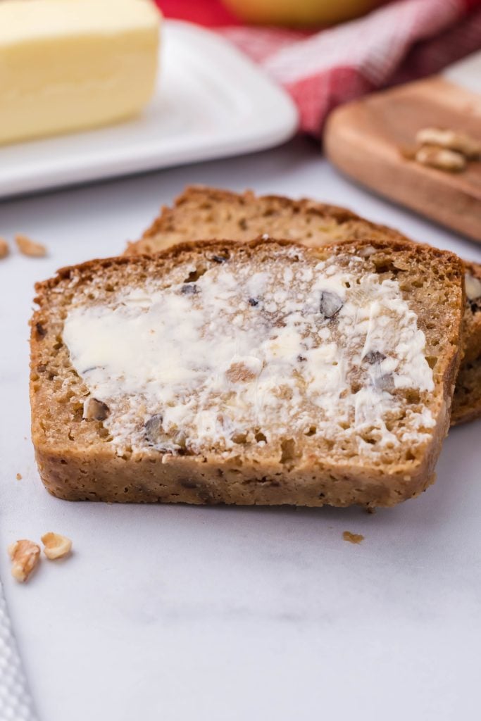 a slice of apple walnut bread spread with fresh butter
