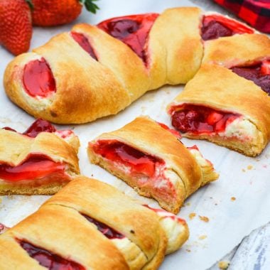 slices of candy cane crescent roll danish with fresh strawberries on a sheet of white parchment paper