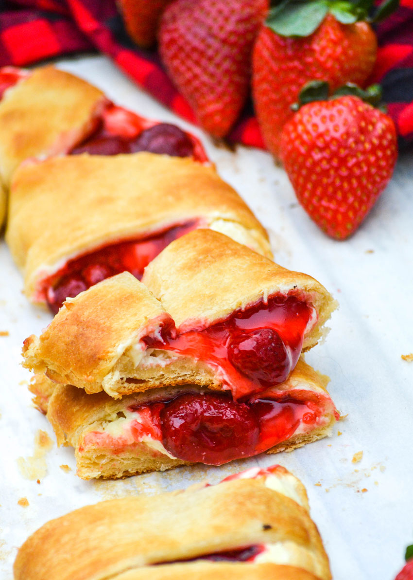 slices of candy cane crescent roll danish with fresh strawberries on a sheet of white parchment paper