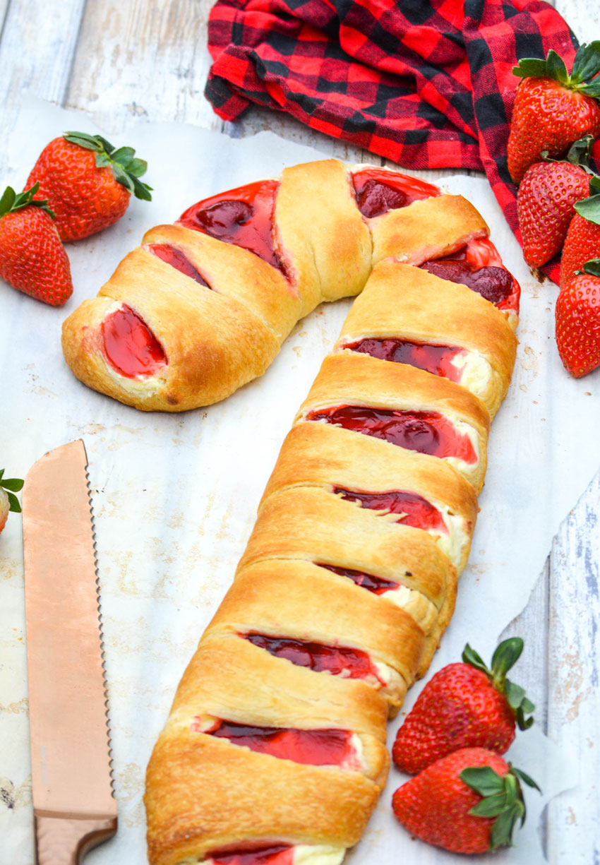 candy cane crescent roll danish with fresh strawberries on a sheet of white parchment paper