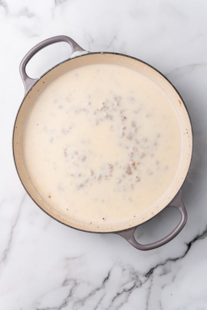homemade sausage gravy in a gray enameled cast iron skillet