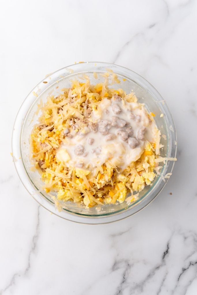 scrambled eggs, cheese, hash browns, and sausage gravy in a glass mixing bowl for breakfast egg roll filling
