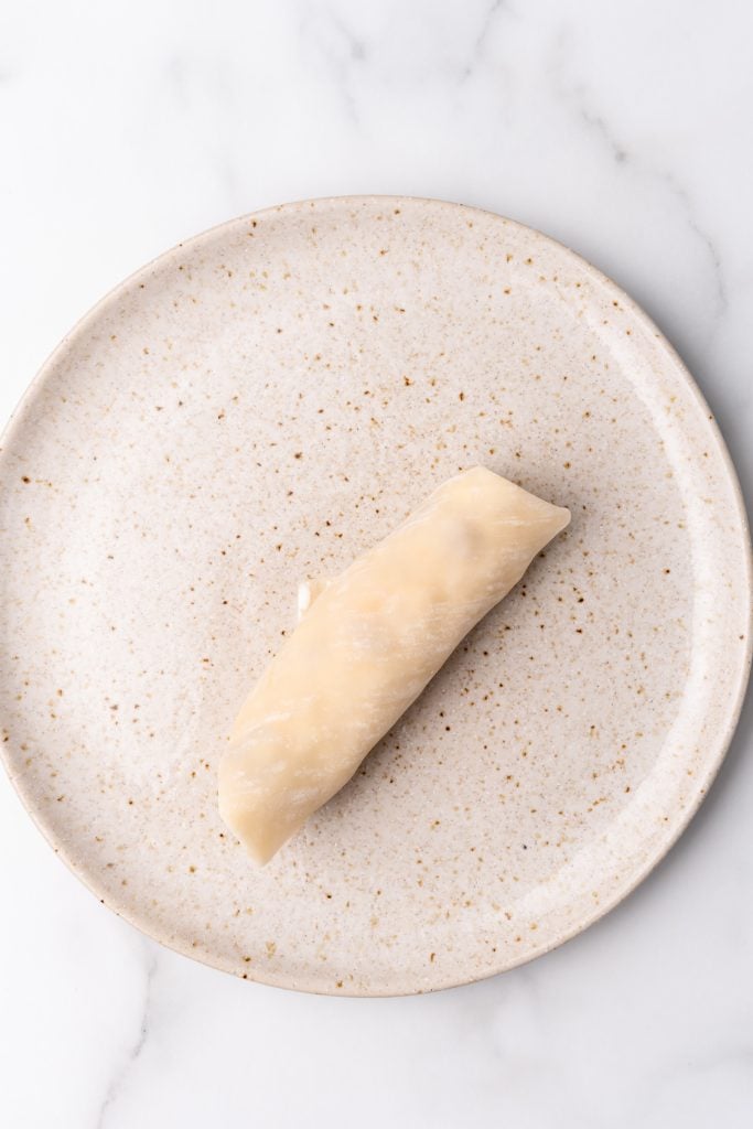 a rolled breakfast egg roll on a speckled ceramic plate