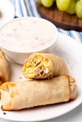 breakfast egg rolls on a white plate next to a small bowl of sausage gravy