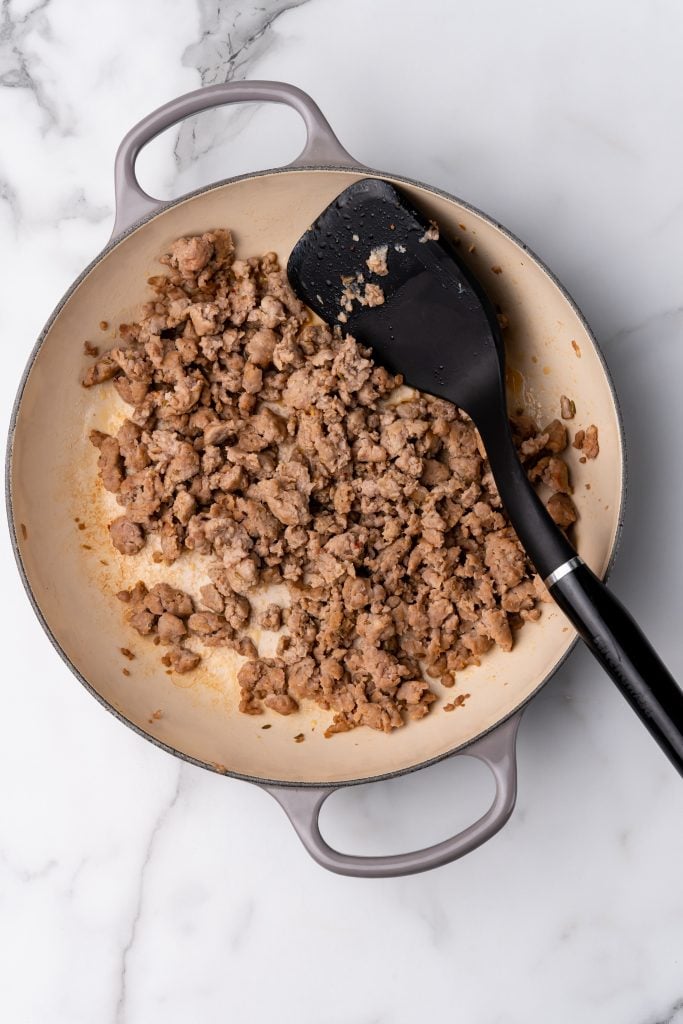 browned crumbled sausage in a skillet with a black spatula on the side