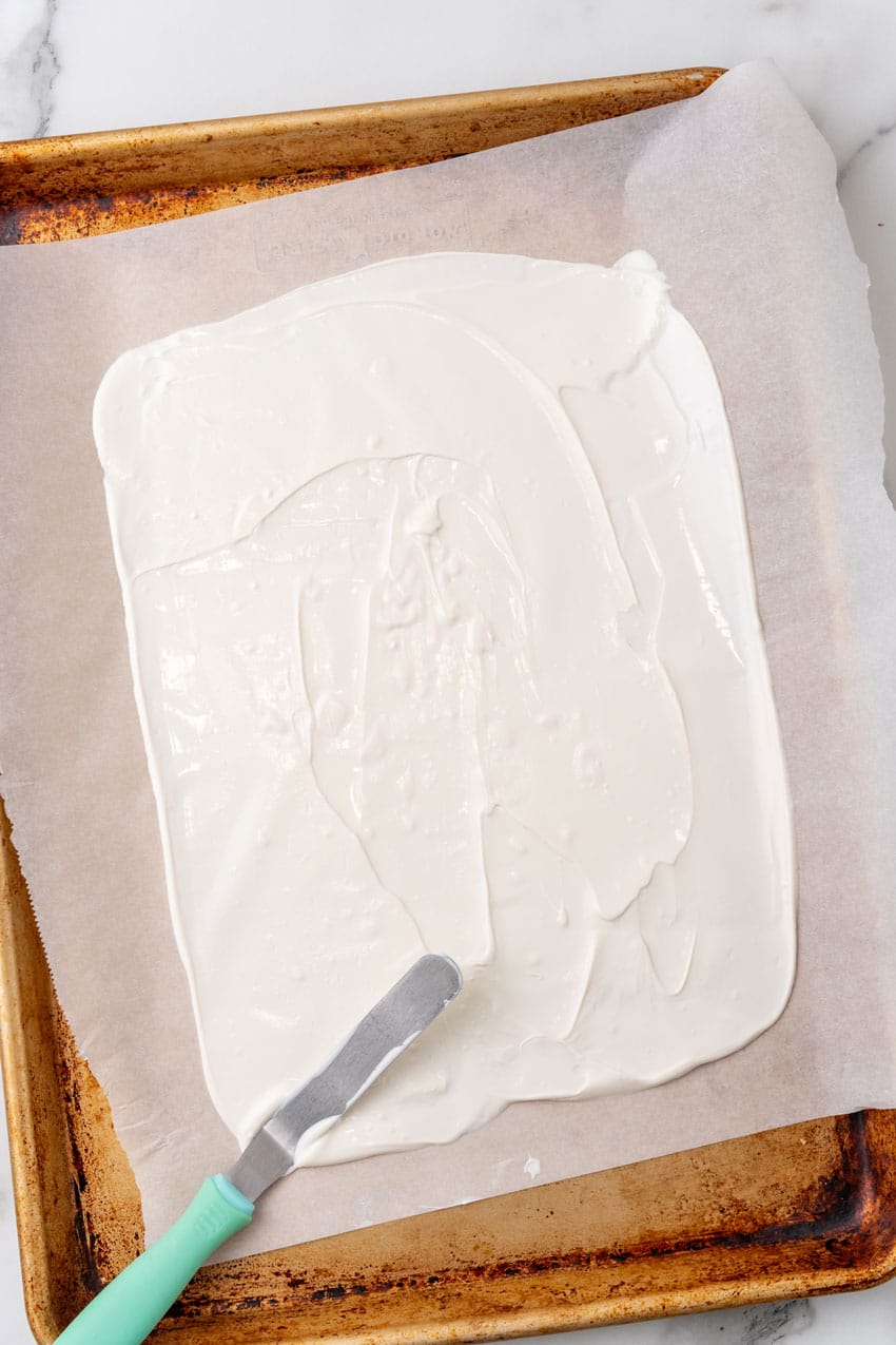 melted white chocolate spread out evenly into a rectangle on a parchment paper lined baking sheet