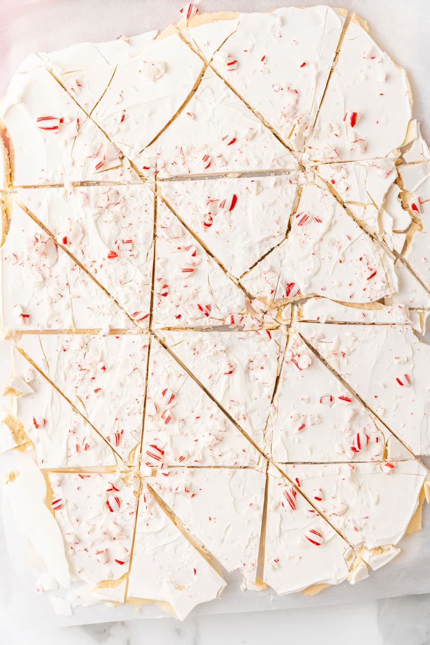 pieces of peppermint sugar cookie bark on a white parchment paper lined baking sheet