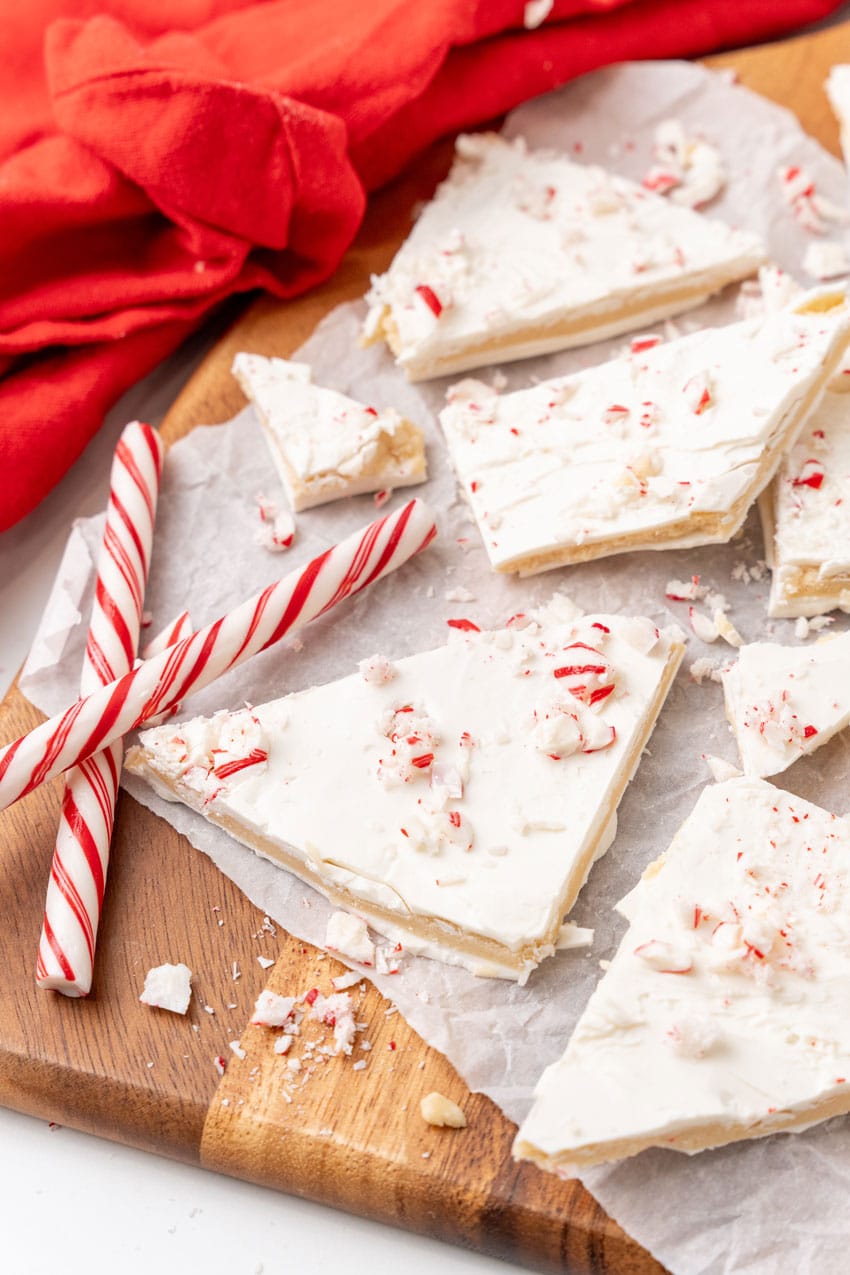 peppermint sugar cookie bark pieces on a parchment paper covered wooden cutting board