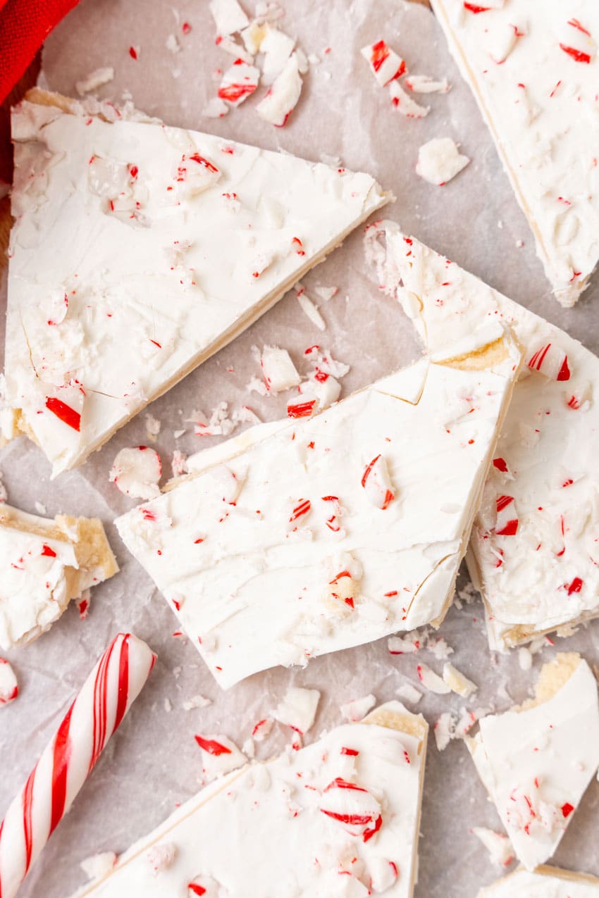 peppermint sugar cookie bark pieces on a parchment paper covered wooden cutting board