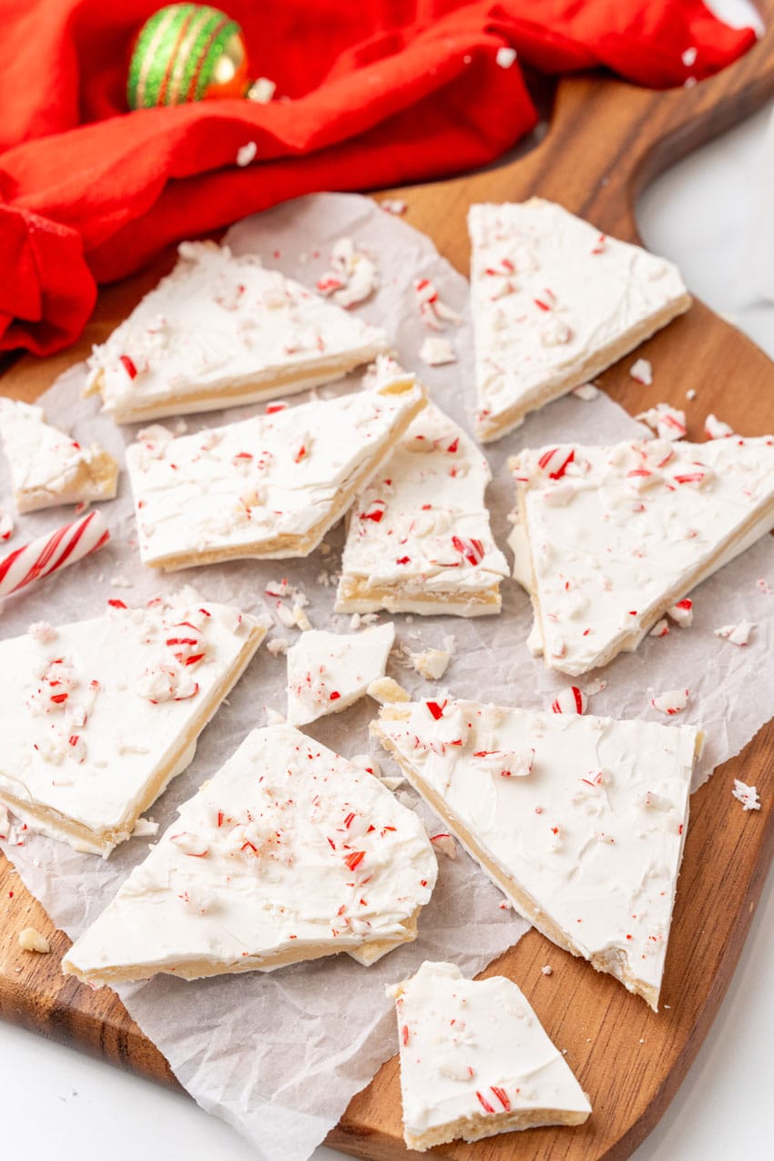 peppermint sugar cookie bark pieces on a parchment paper covered wooden cutting board