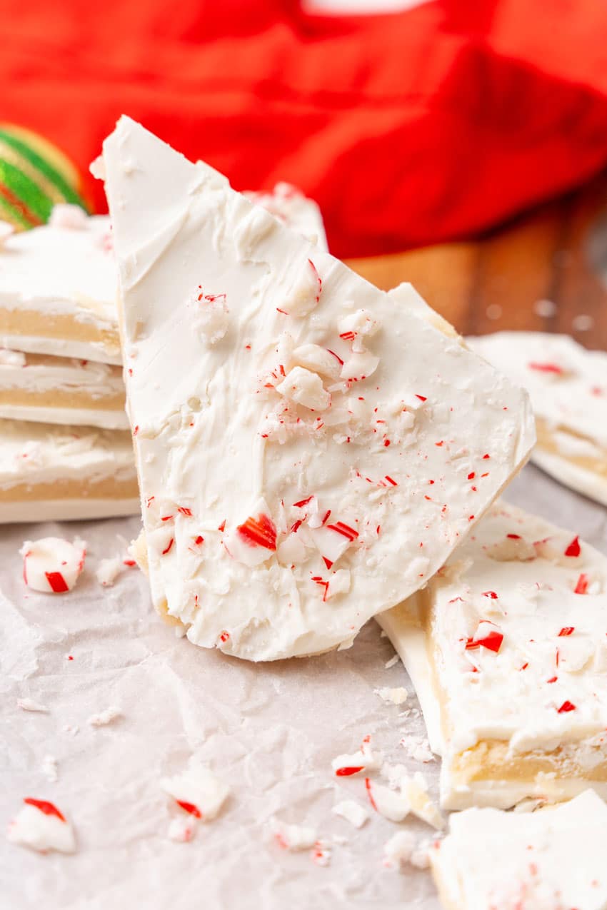 peppermint sugar cookie bark pieces on a parchment paper covered wooden cutting board